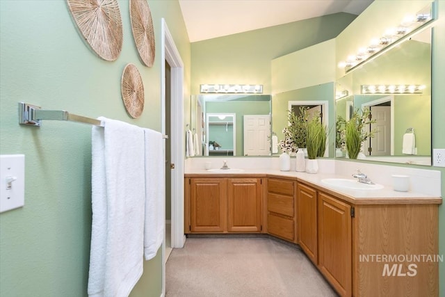 bathroom featuring vaulted ceiling, double vanity, and a sink