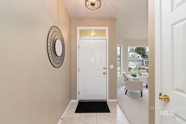 entryway featuring light tile patterned floors, light colored carpet, and baseboards