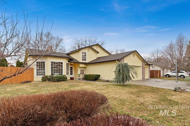 traditional-style home with an attached garage, concrete driveway, a front yard, and fence