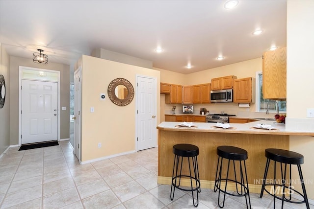 kitchen with baseboards, light countertops, light tile patterned floors, appliances with stainless steel finishes, and a peninsula