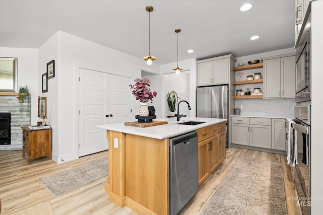 4875 N Glenrock Ave, Meridian, ID 83646 - kitchen featuring an island with sink, stainless steel appliances, open shelves, light wood-style floors, and a sink