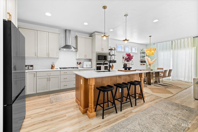4875 N Glenrock Ave, Meridian, ID 83646 - kitchen with stainless steel appliances, light countertops, light wood finished floors, and wall chimney exhaust hood
