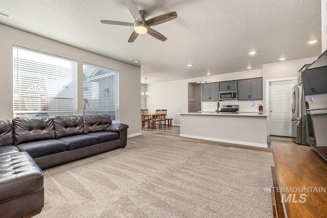 living area featuring light carpet, ceiling fan, a textured ceiling, and recessed lighting