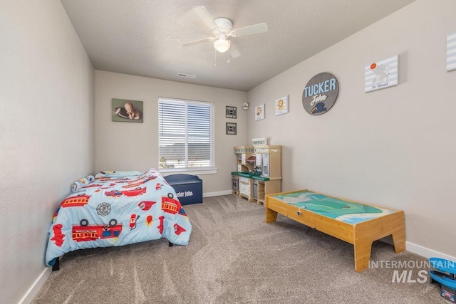 carpeted bedroom with a textured ceiling, a ceiling fan, visible vents, and baseboards