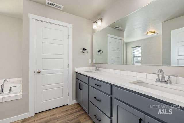 full bath featuring visible vents, a sink, and wood finished floors