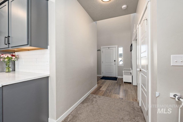 hallway featuring a textured ceiling, wood finished floors, carpet flooring, and baseboards