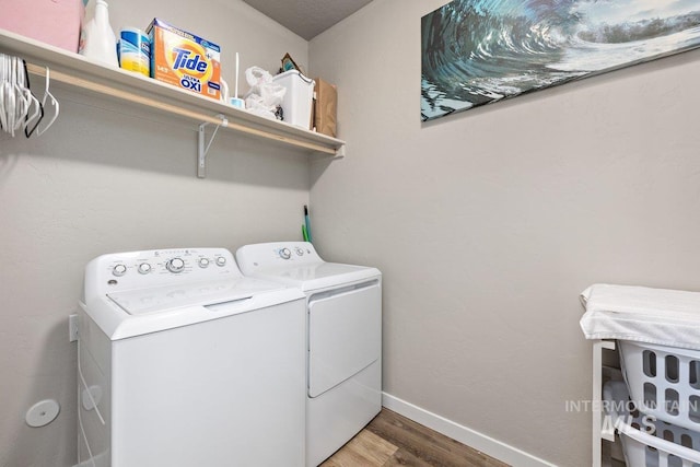 laundry area featuring laundry area, baseboards, washing machine and clothes dryer, and wood finished floors