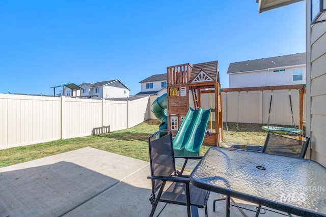 view of jungle gym featuring a patio, outdoor dining area, and a fenced backyard