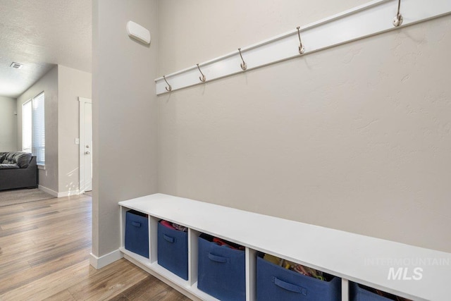 mudroom featuring baseboards, a textured ceiling, visible vents, and light wood-style floors