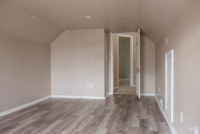 bonus room featuring a textured ceiling, light wood-type flooring, and vaulted ceiling