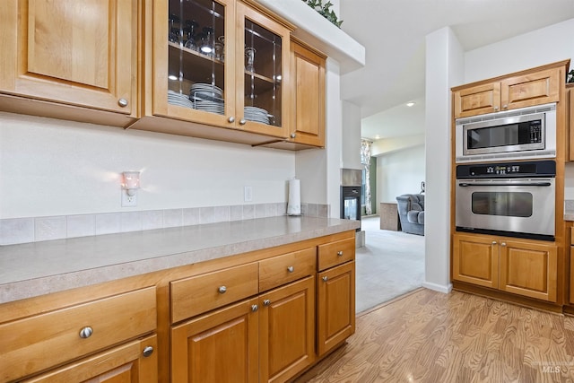 9788 Hwy 78, Hammett, ID 83627 - kitchen featuring stainless steel microwave, light wood-type flooring, glass insert cabinets, light countertops, and brown cabinetry
