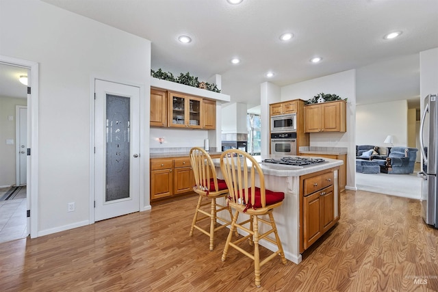 9788 Hwy 78, Hammett, ID 83627 - kitchen featuring a kitchen breakfast bar, light countertops, a kitchen island, brown cabinetry, and stainless steel appliances