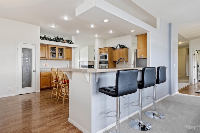9788 Hwy 78, Hammett, ID 83627 - kitchen featuring a breakfast bar, glass insert cabinets, light countertops, brown cabinets, and appliances with stainless steel finishes
