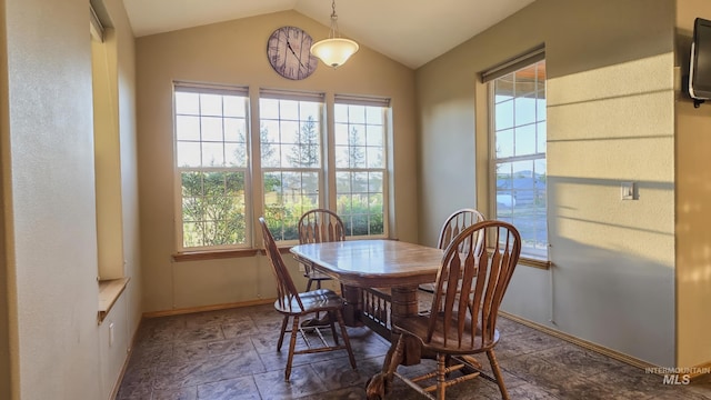 dining space featuring baseboards, stone finish floor, lofted ceiling, and a healthy amount of sunlight