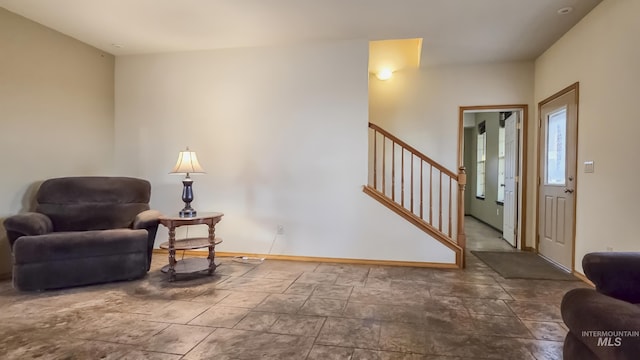 sitting room with stone finish flooring, stairs, and baseboards