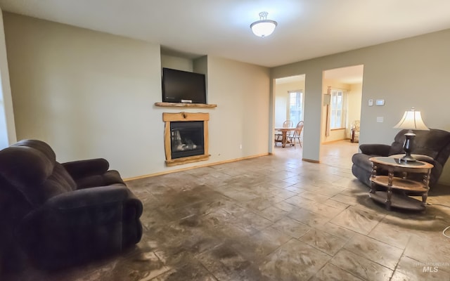 living area featuring a glass covered fireplace and baseboards