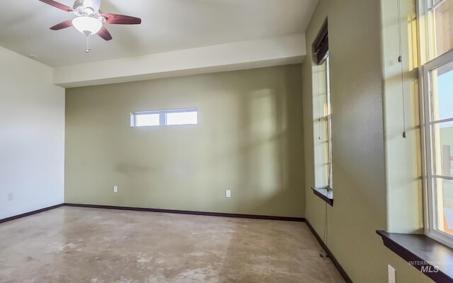 empty room with concrete flooring, baseboards, and a ceiling fan