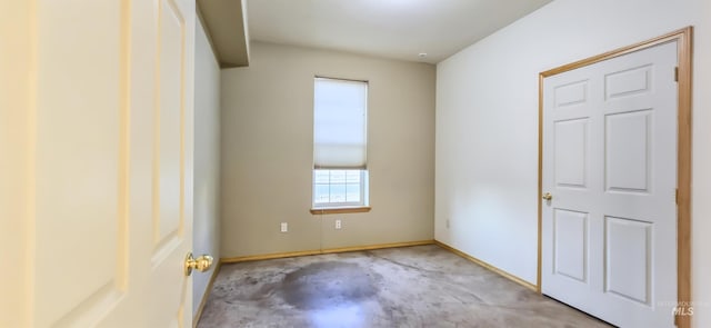 empty room with concrete flooring and baseboards