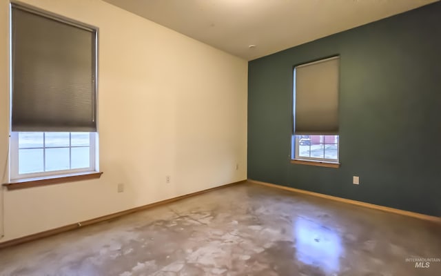 empty room featuring concrete floors and baseboards