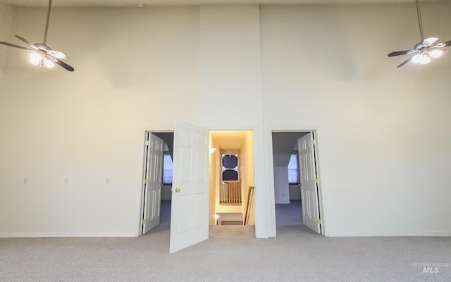 interior space featuring a high ceiling, baseboards, a ceiling fan, and carpet floors