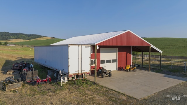 view of outbuilding with a rural view, an outdoor structure, and fence