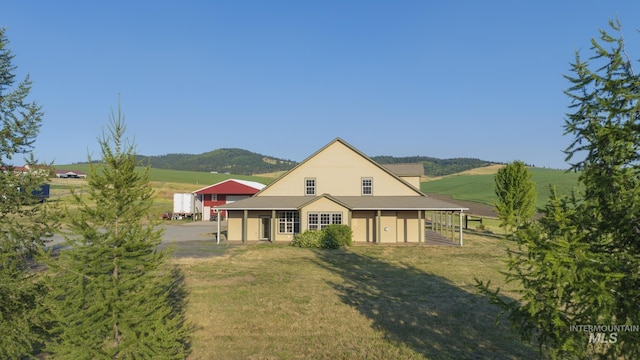 rear view of property with a yard, roof with shingles, and dirt driveway