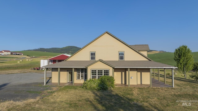 rear view of house featuring a shingled roof and a lawn