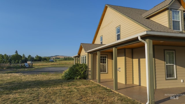 view of side of property featuring a yard and a shingled roof