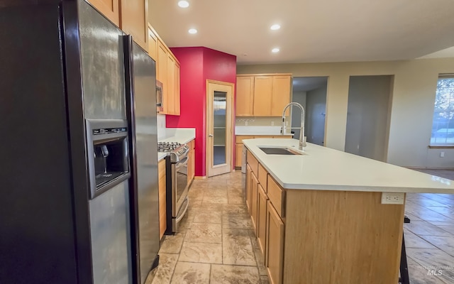 kitchen featuring recessed lighting, a kitchen island with sink, light countertops, a sink, and stainless steel appliances