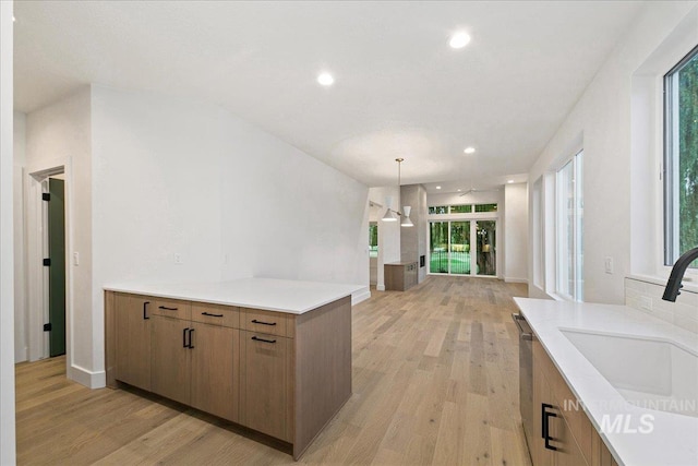 kitchen featuring recessed lighting, a peninsula, a sink, light wood-style floors, and light countertops