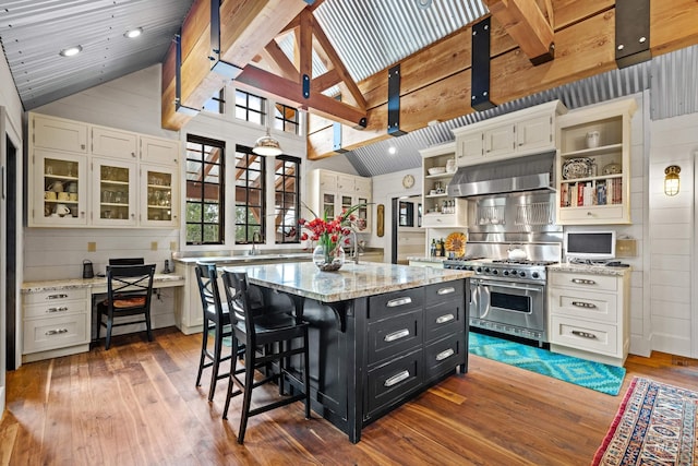 kitchen with open shelves, dark cabinets, high end range, under cabinet range hood, and wood-type flooring
