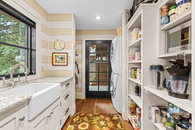 pantry featuring stacked washing machine and dryer and a sink