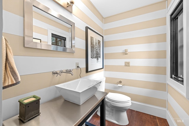 half bath with toilet, wood finished floors, and vanity