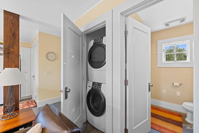 clothes washing area featuring stacked washer / drying machine and baseboards