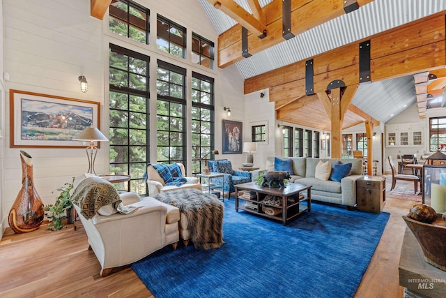 living area featuring high vaulted ceiling, wood finished floors, beam ceiling, and wood walls