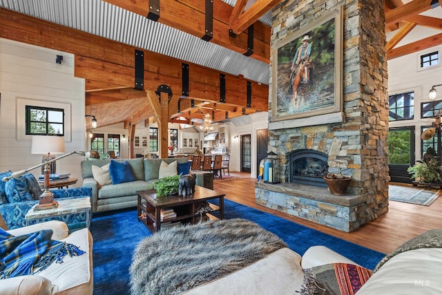 living room featuring beamed ceiling, wood finished floors, high vaulted ceiling, and a fireplace