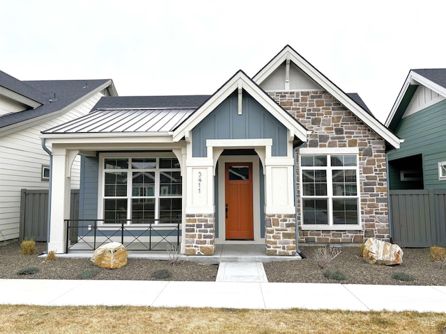 view of front of home with a standing seam roof, stone siding, metal roof, and board and batten siding