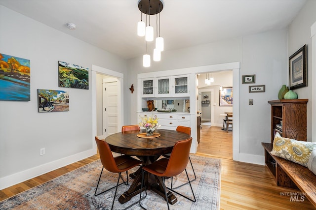 dining space featuring baseboards and light wood-type flooring