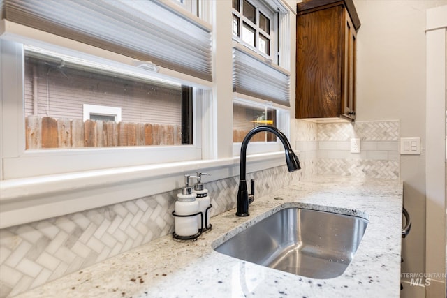 room details with backsplash, light stone countertops, and a sink