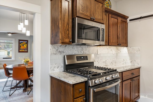 kitchen with stainless steel appliances, light stone countertops, pendant lighting, and decorative backsplash