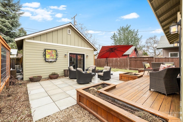 wooden terrace with an outdoor living space with a fire pit and a fenced backyard