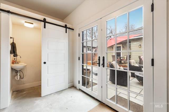 entryway featuring a barn door, baseboards, concrete flooring, and french doors