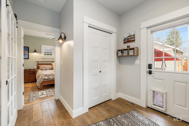 entryway with hardwood / wood-style flooring, a barn door, visible vents, and baseboards