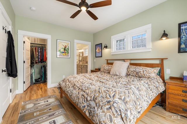 bedroom with a walk in closet, a closet, ensuite bath, and light wood finished floors