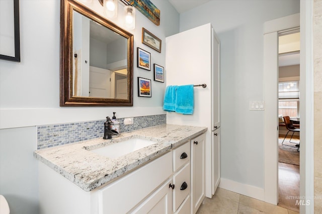 ensuite bathroom featuring tile patterned floors, backsplash, connected bathroom, baseboards, and vanity