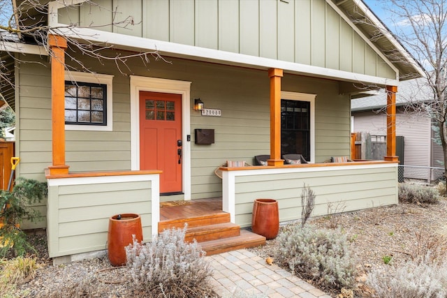 view of exterior entry featuring a porch, fence, and board and batten siding