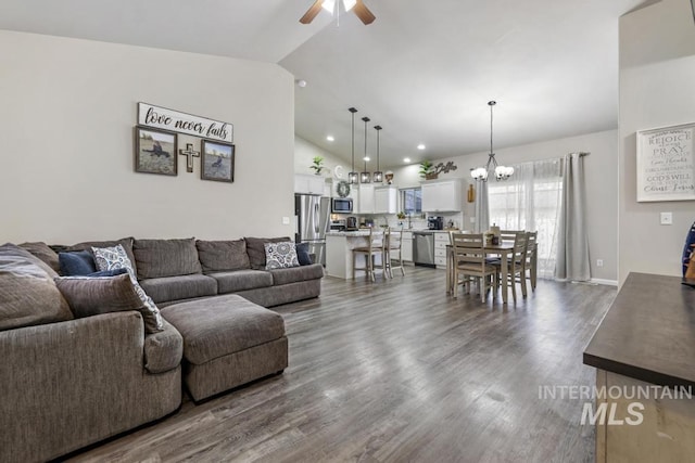 living room with vaulted ceiling, dark wood-type flooring, and ceiling fan with notable chandelier