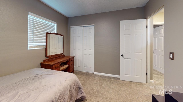 bedroom with baseboards, a closet, and light colored carpet