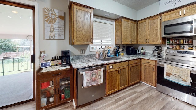 kitchen with stainless steel appliances, brown cabinetry, and a sink