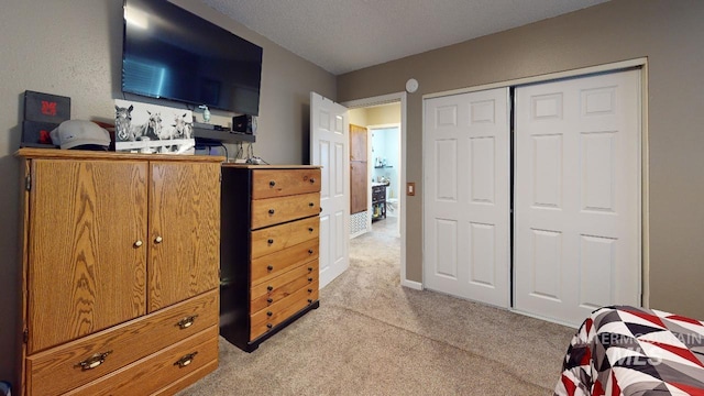 bedroom with a closet, a textured ceiling, and light colored carpet